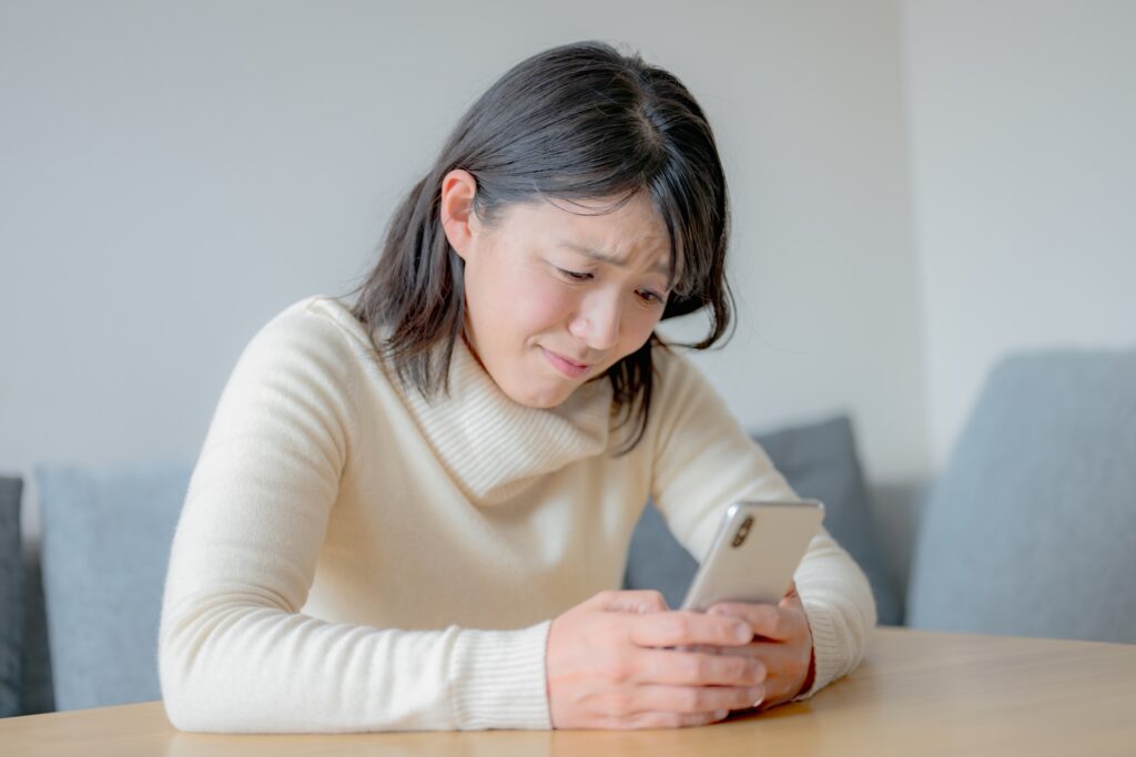 スマホと顔しかめる若い女性