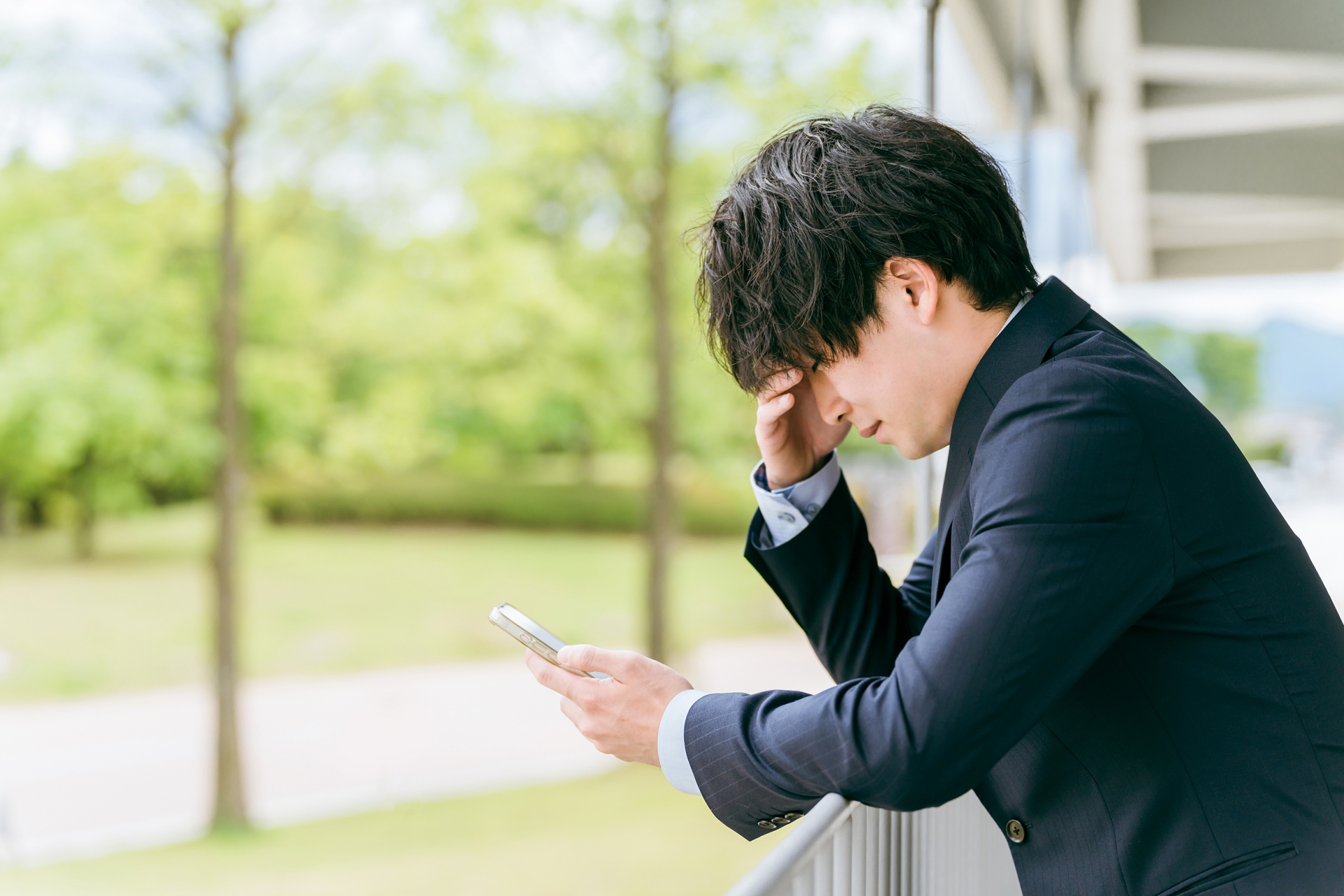 スマホを見る悩むビジネスマン（誹謗中傷）