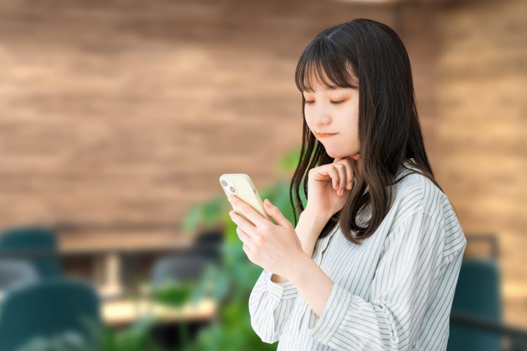 スマホを見て考える女性・ビジネスウーマン